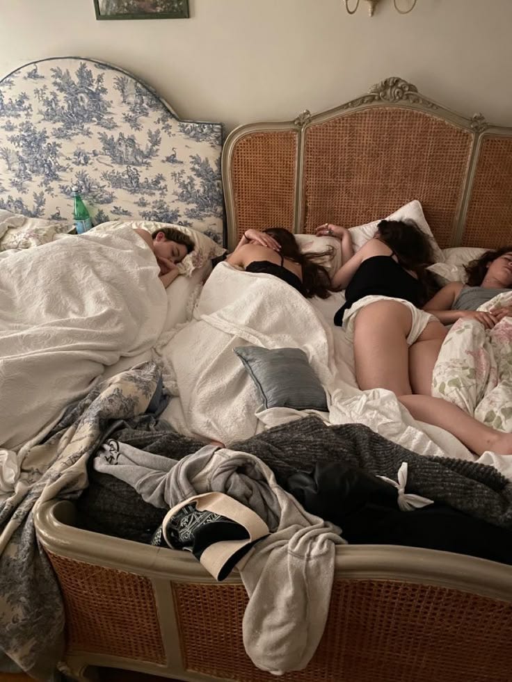 This may contain: three women laying in bed with their heads on each other's backs as they sleep