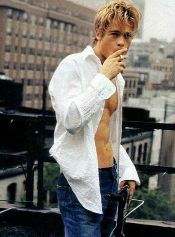 This may contain: a shirtless man standing next to a bike on a roof with buildings in the background