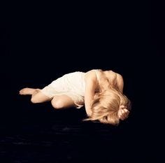 This may contain: a woman laying on the ground with her hands behind her head and legs spread out