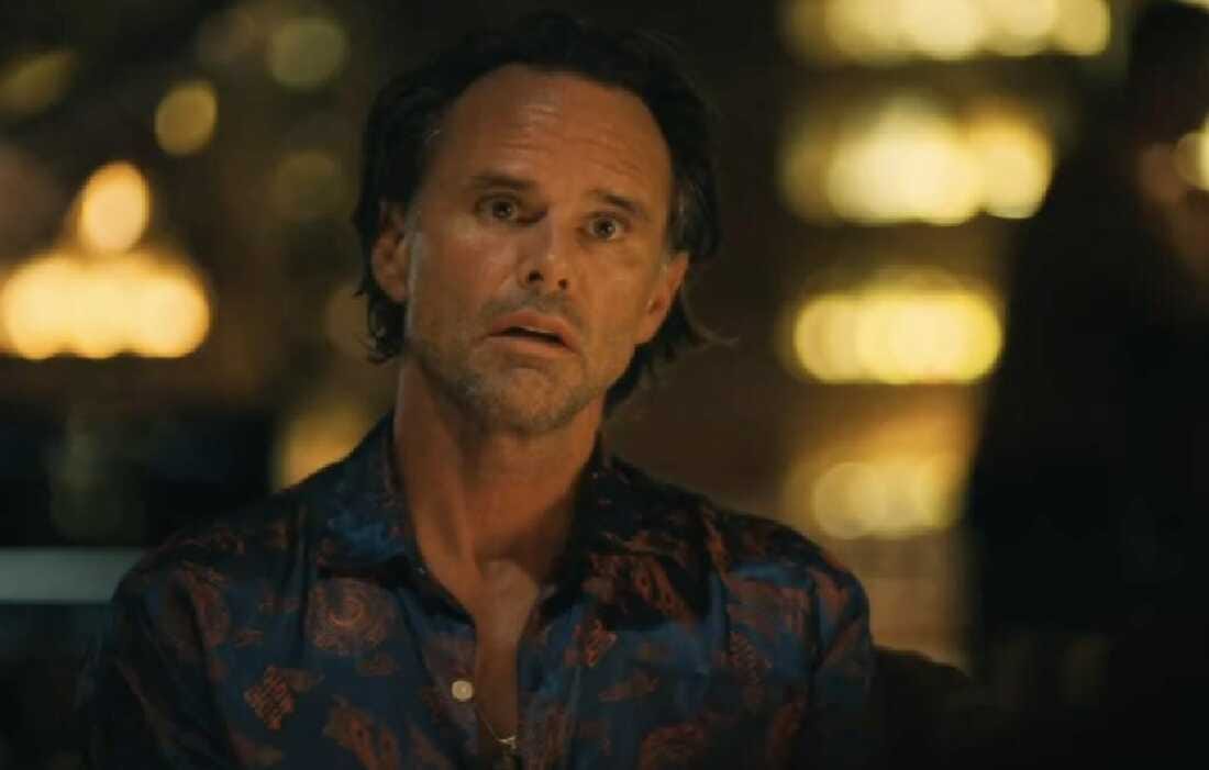 A white man sits wide eye and agape in a still shot from The White Lotus season 3. 