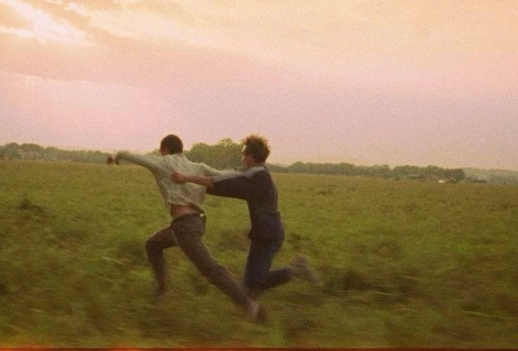 This may contain: two young men playing with a frisbee in a grassy field at sunset or dawn