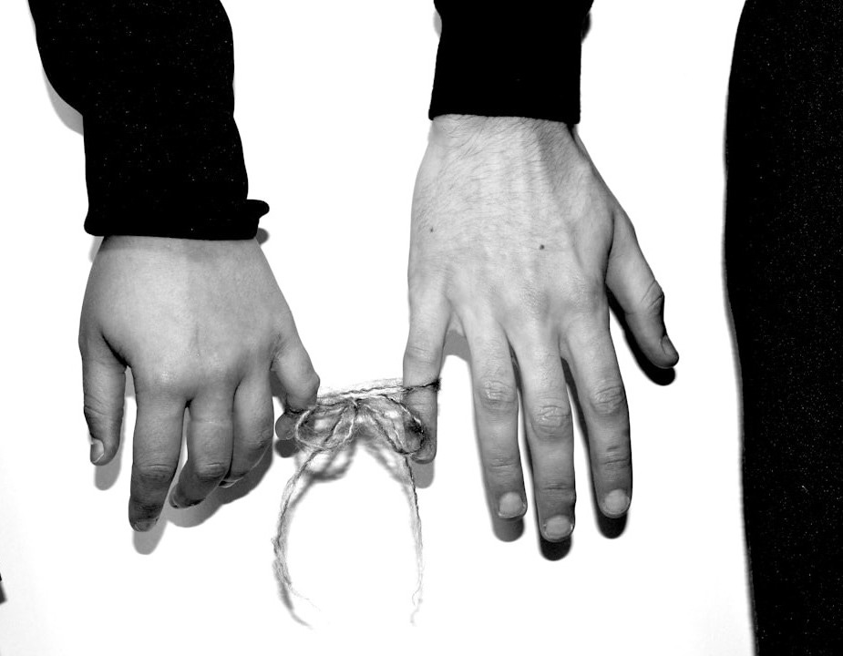 two hands holding a string tied to a tie