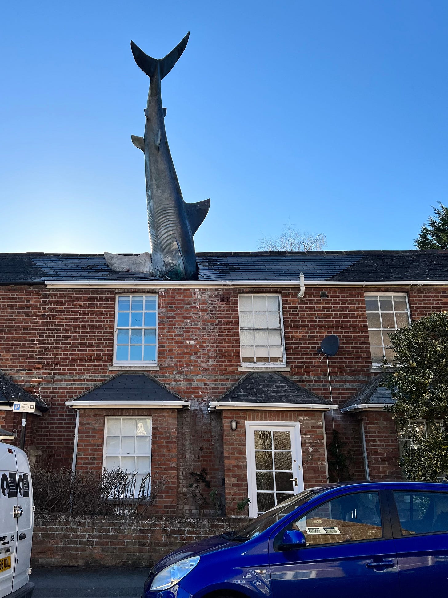 On a bright sunny day there is not a cloud in the sky on this street of terraced two-story redbrick houses. In the roof of one of the house, the tail and body of a full size Great White shark is crashing through the tiled roof. This is the Headington Shark in Oxford, and was an installed in the 1980s as a form or protest art to comment on the effects of indiscriminate bombing. Bill Heine, the owner of the house who co-conceived the project, said: "The shark was to express someone feeling totally impotent and ripping a hole in their roof out of a sense of impotence and anger and desperation... It is saying something about CND, nuclear power, Chernobyl and Nagasaki"