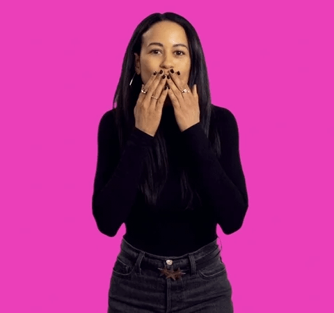 A woman stands in front of a pink background and blows a kiss A woman stands in front of a pink background and blows a kiss