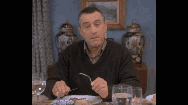 a man is sitting at a table with a plate of food and a fork in his hand a man is sitting at a table with a plate of food and a fork in his hand
