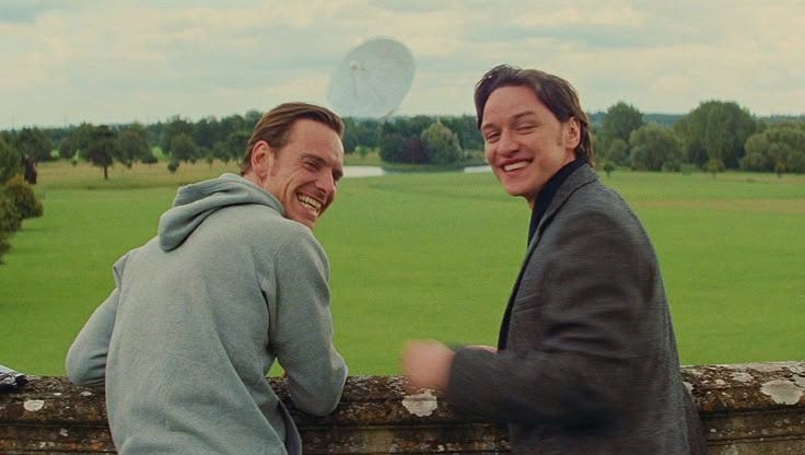 This may contain: two men standing next to each other near a field