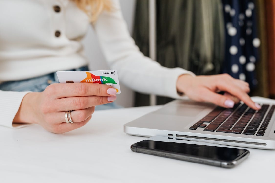 Free Close-up of a woman using a credit card for online shopping on a laptop, emphasizing digital transactions. Stock Photo