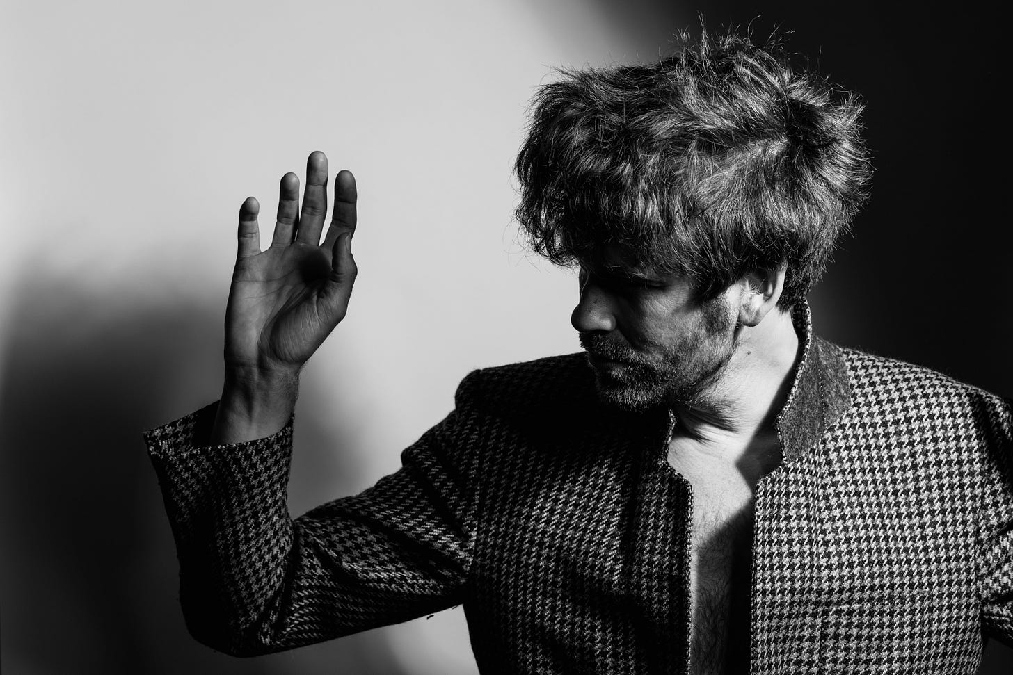 A black and white photo of singer Fyfe Dangerfield. He is partially obscured by shadow, and his hand is raised enigmatically. A black and white photo of singer Fyfe Dangerfield. He is partially obscured by shadow, and his hand is raised enigmatically.