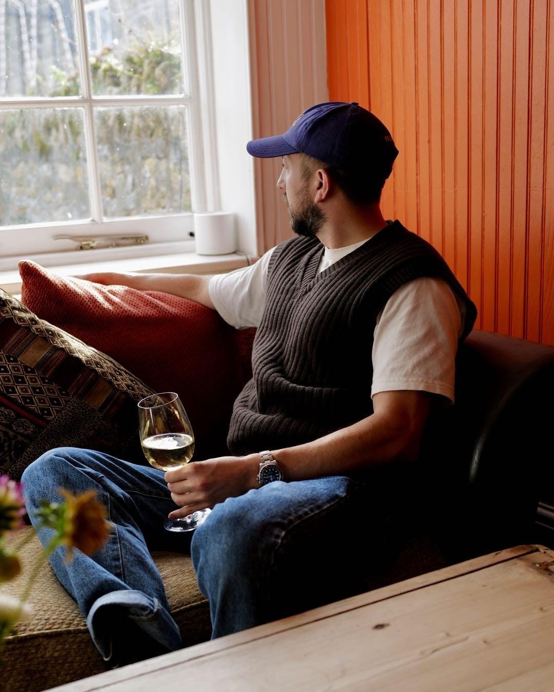 A person sitting on a couch holding a glass of wine

Description automatically generated
