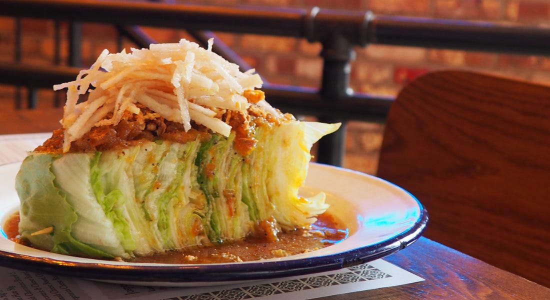 A plate of iceberg lettuce with pear on top on a wooden table A plate of iceberg lettuce with pear on top on a wooden table