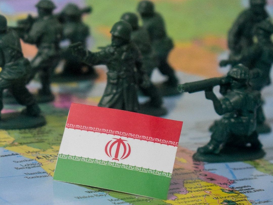 Toy soldiers surround the flag of iran on a map.