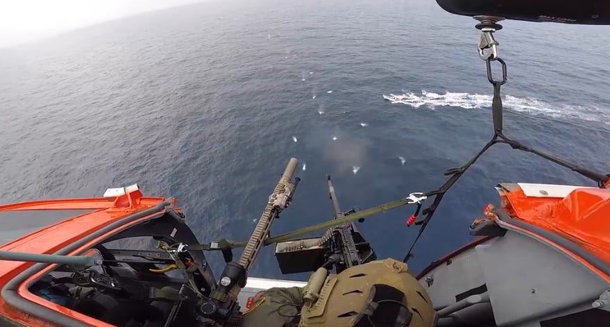 A Coast Guard Helicopter Interdiction Tactical Squadron gunner fires warning shots across the bow of a fleeing drug smuggling boat before shooting out its outboard motors off the Colombian coast.