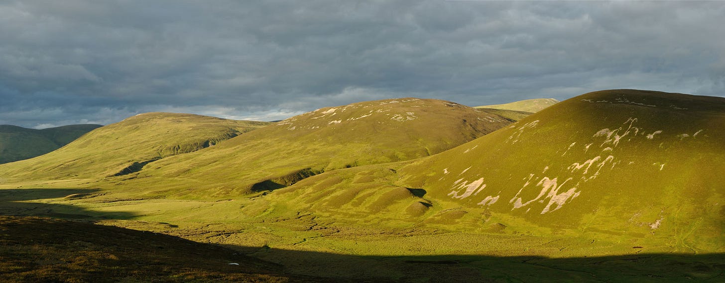 rounded hills, brightly sunlit below cloud