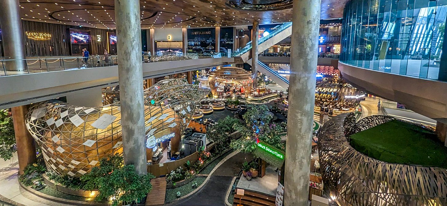 Interior of a mall showing marble columns and fancy shops. 