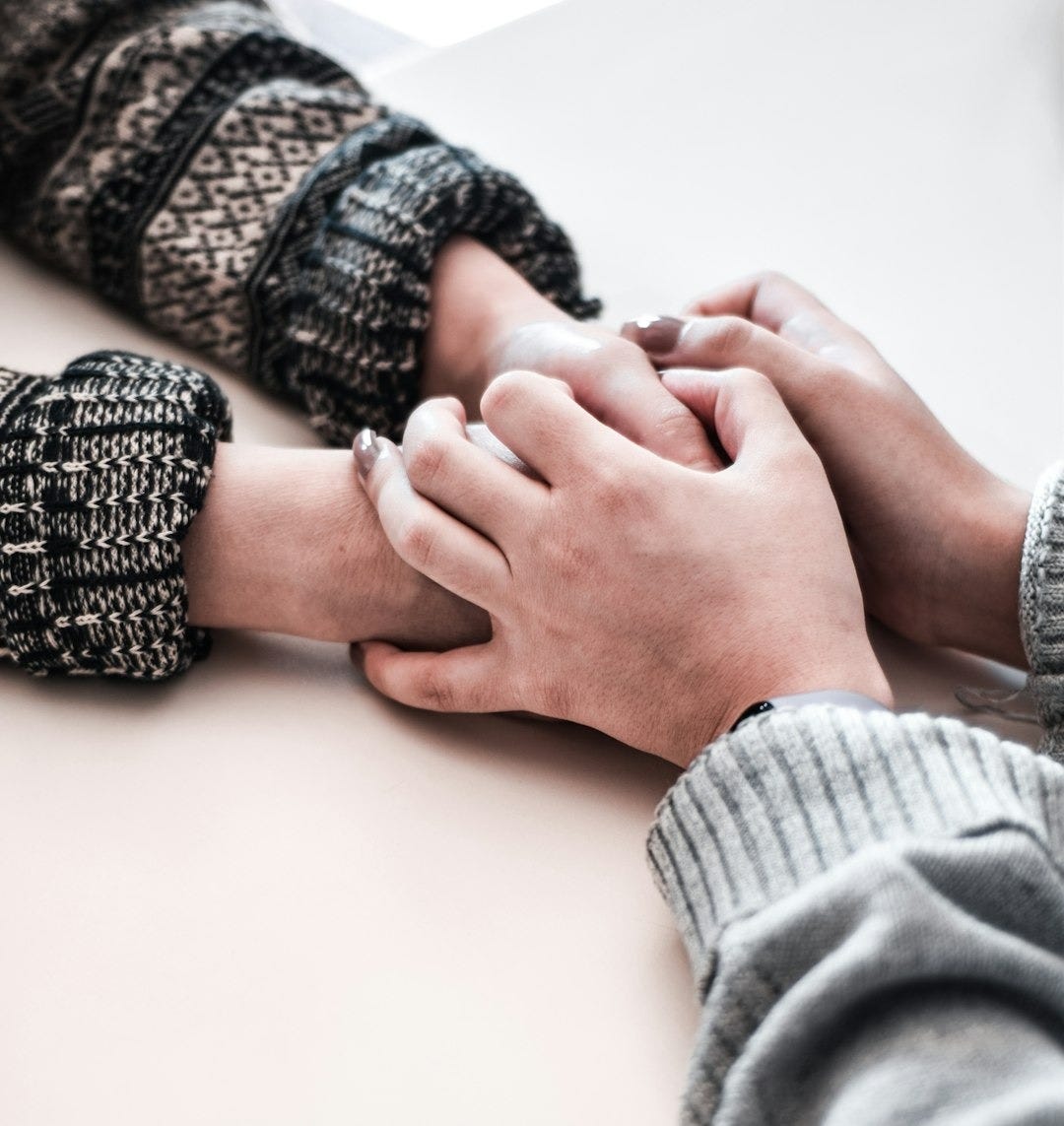 person in gray long sleeve shirt holding persons hand