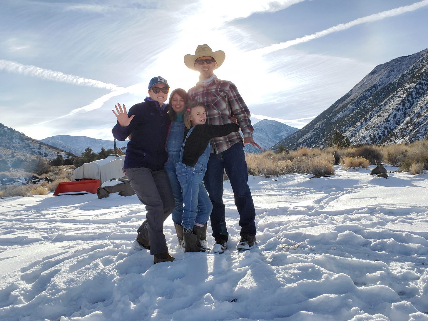 Charlotte, C, L, and Eric standing outside in the snow and smiling at the camera.