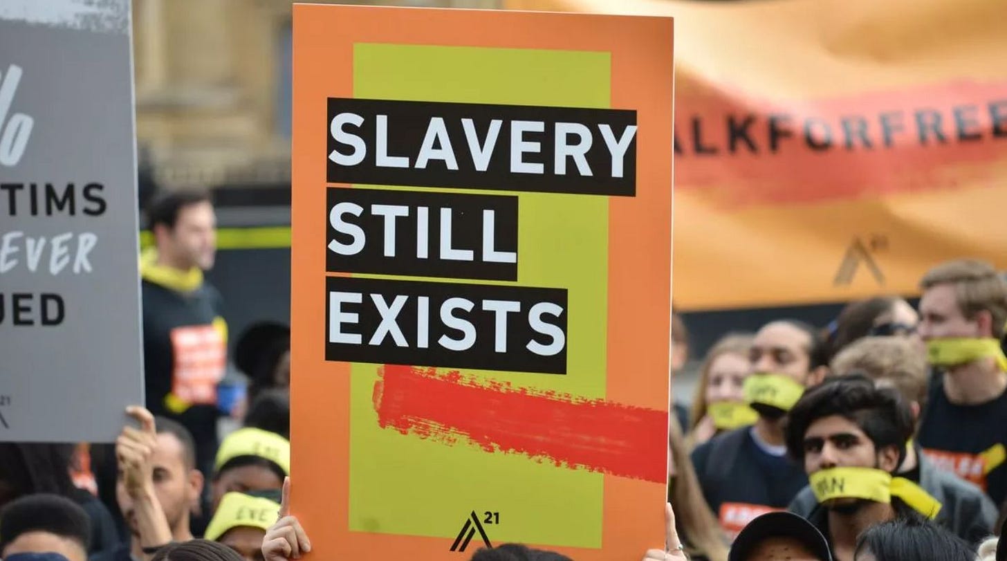 People demonstrating and holding up a sign saying Slavery Still Exists