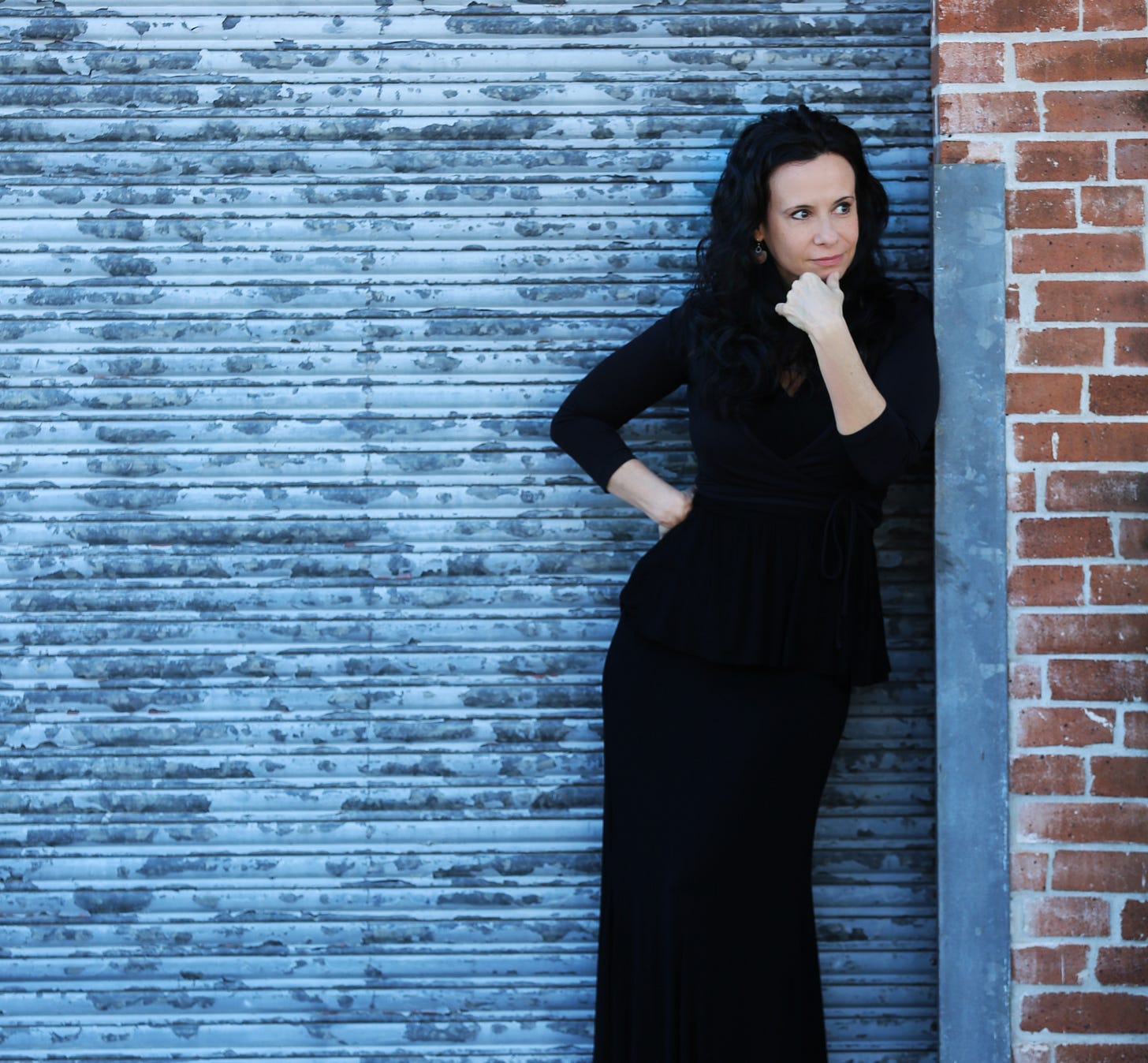 Misha Penton in front of distressed industrial doors in a long black dress