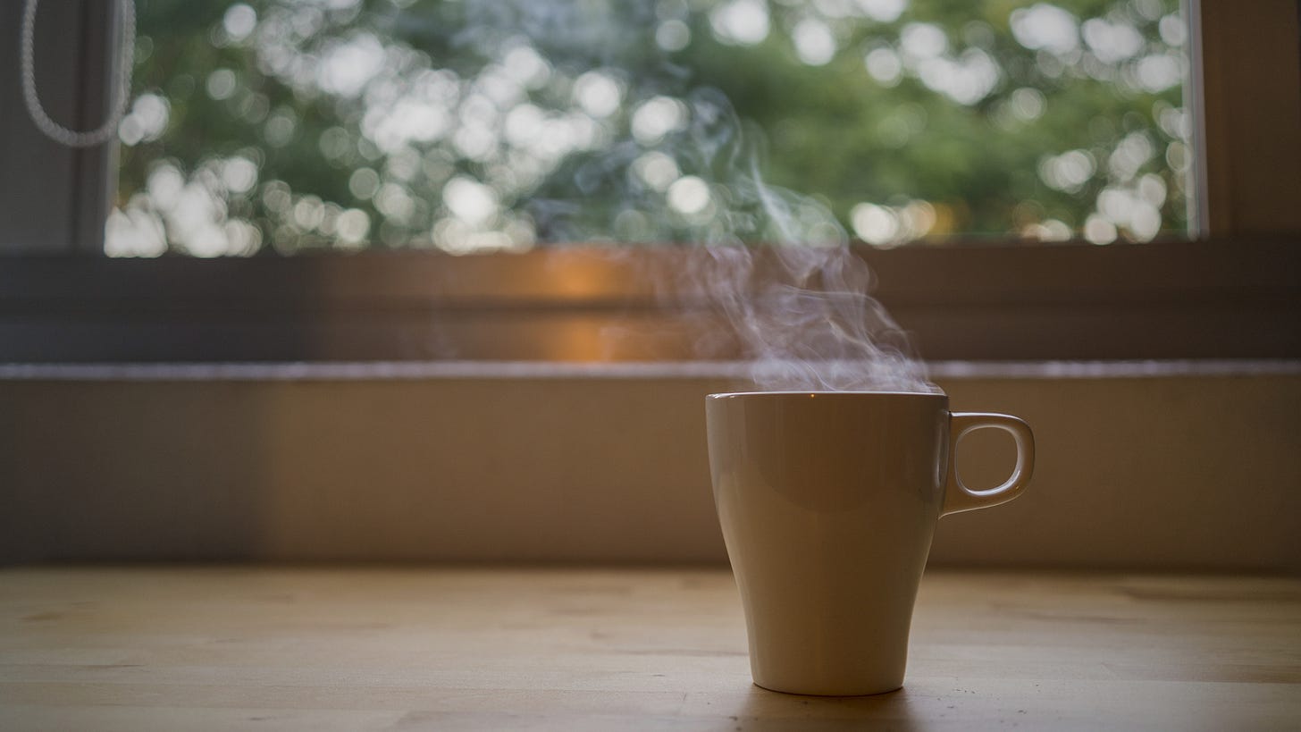 A single coffee mug sits in soft morning light on a wooden table