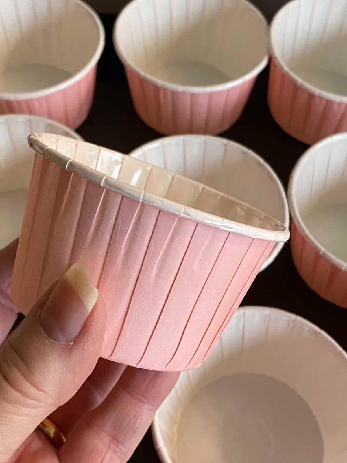 Placing 12 large pink muffin cups on a baking tray for wholesome apple and oat breakfast muffins. Placing 12 large pink muffin cups on a baking tray for wholesome apple and oat breakfast muffins.