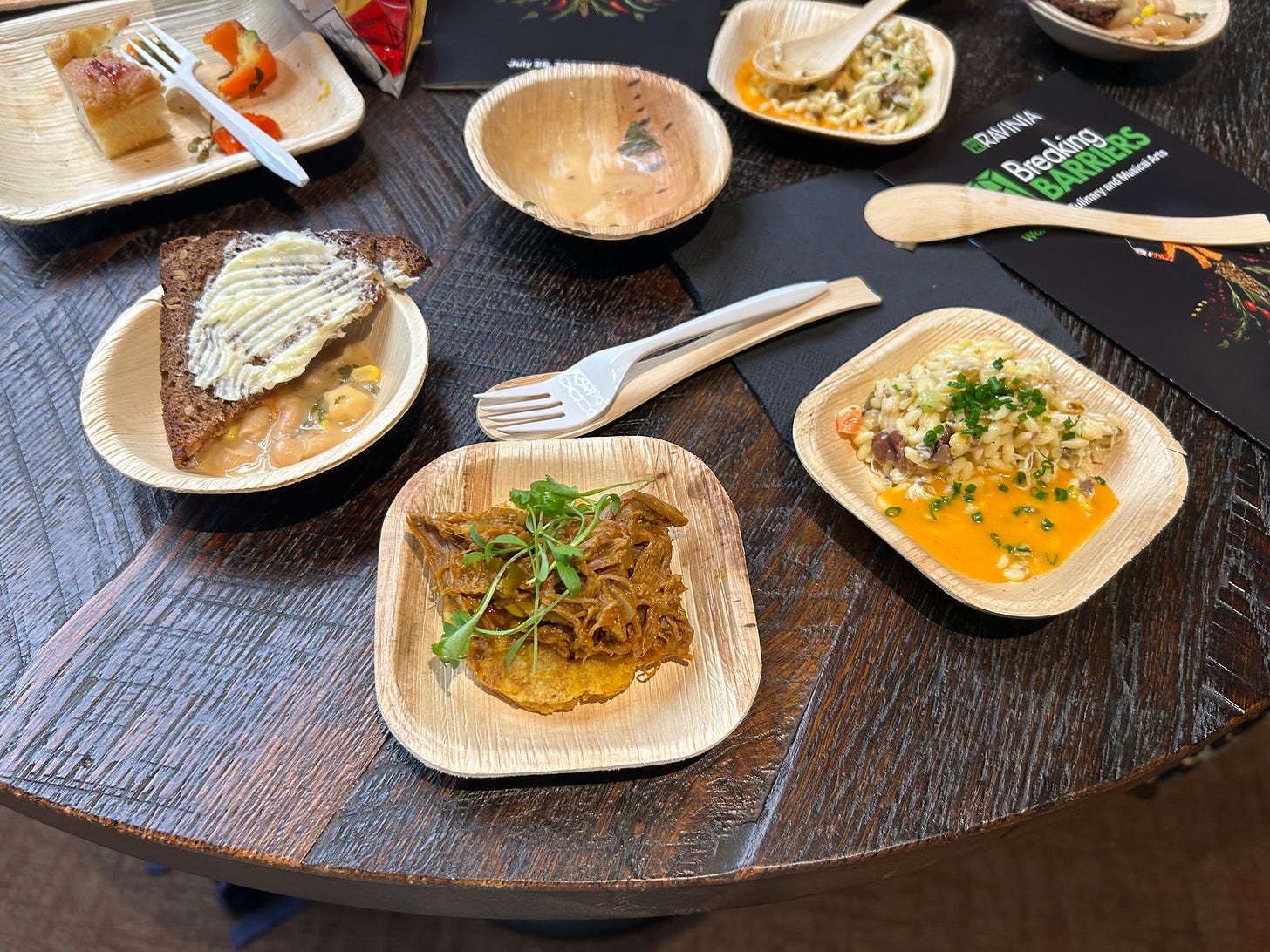 A detail of some food on a dark wood table, some of it half eaten, from the Breaking Barriers Festival's featured chefs.