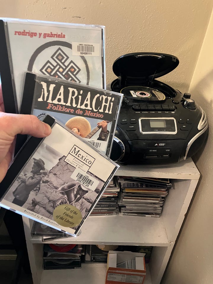 Four photos of a compact disc music player and three Spanish music compact discs (CDs)