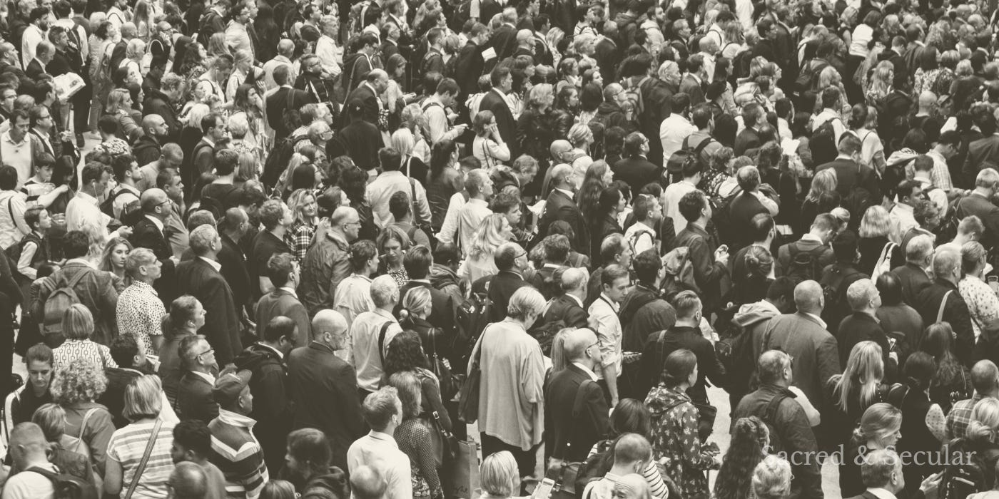 A group of people sitting and observing a public scene from a distance, not participating.