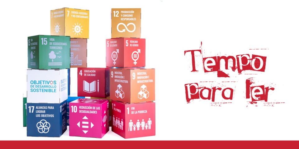 #descrevemospravocê  A imagem apresenta, à esquerda, uma pilha de cubos coloridos representando os 17 Objetivos de Desenvolvimento Sustentável (ODS) da ONU. Cada cubo tem uma cor distinta, número, ícone e o nome do objetivo em espanhol. Os blocos estão empilhados de forma irregular, criando uma composição visual que remete a um jogo de construção. Os objetivos visíveis incluem temas como erradicação da pobreza, igualdade de gênero, educação de qualidade, ação contra as mudanças climáticas, energia limpa, consumo responsável, parcerias e redução das desigualdades. Um dos cubos em destaque traz o texto "Objetivos de Desarrollo Sostenible" com a logomarca dos ODS — um círculo formado por segmentos coloridos.  À direita da imagem, sobre um fundo branco, aparece a frase “Tempo para ler” escrita em letras vermelhas, com um estilo tipográfico irregular, como se tivesse sido carimbada ou pintada de forma artesanal. A palavra "ler" aparece parcialmente cortada na parte inferior, reforçando o efeito visual artístico. Na base da imagem, uma faixa horizontal vermelha atravessa toda a largura.  A imagem combina elementos gráficos dos ODS com uma chamada visual à leitura, sugerindo que o ato de ler pode estar ligado à conscientização e ao desenvolvimento sustentável.