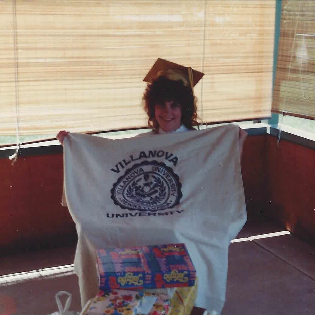 High school grad who's unwrapping gifts, holds up a Villanova University beach towel High school grad who's unwrapping gifts, holds up a Villanova University beach towel