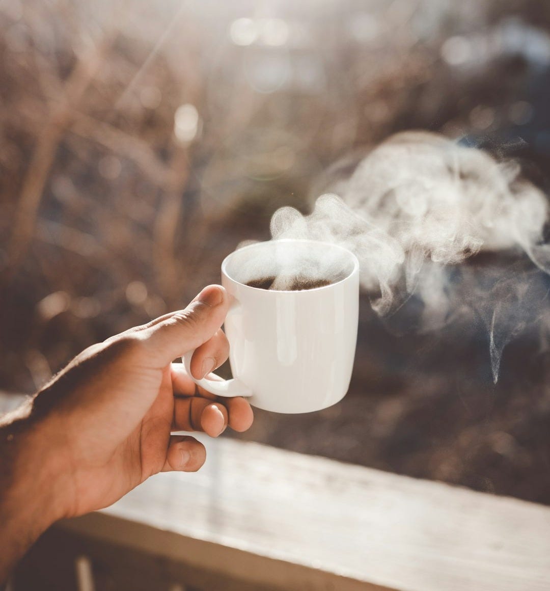 person holding white ceramic cup with hot coffee