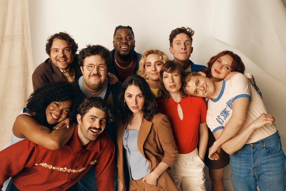 Celeste Dring, Hammed Animashaun, Larry Dean, George Fouracres, Jack Shep, Ayoade Bamgboye, Al Nash, Paddy Young, Ania Magliano, Annabel Marlow and Emma Sidi all stood in a huddle next to one another, posing and smiling ahead.