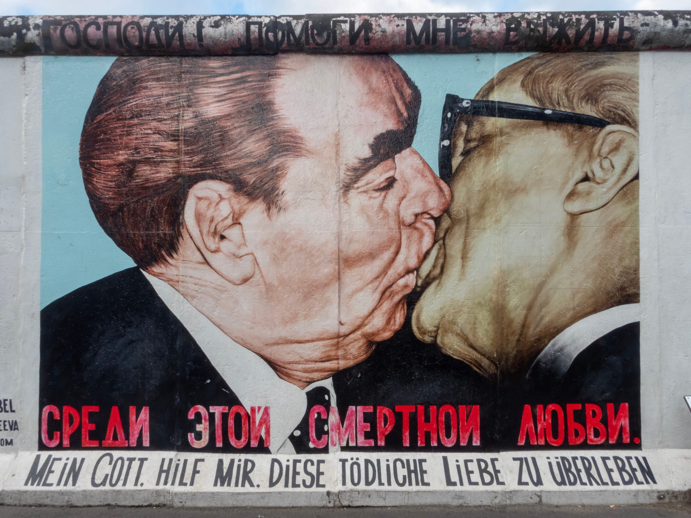 A piece of the Berlin Wall with a graffiti painting showing Brezhnev and Honecker kissing — and a text in German saying: My God, Help Me to Survive This Deadly Love (and a brief version of the same text in Russian). The painting was made in 1900 by Dmitri Vrubel. A piece of the Berlin Wall with a graffiti painting showing Brezhnev and Honecker kissing — and a text in German saying: My God, Help Me to Survive This Deadly Love (and a brief version of the same text in Russian). The painting was made in 1900 by Dmitri Vrubel.