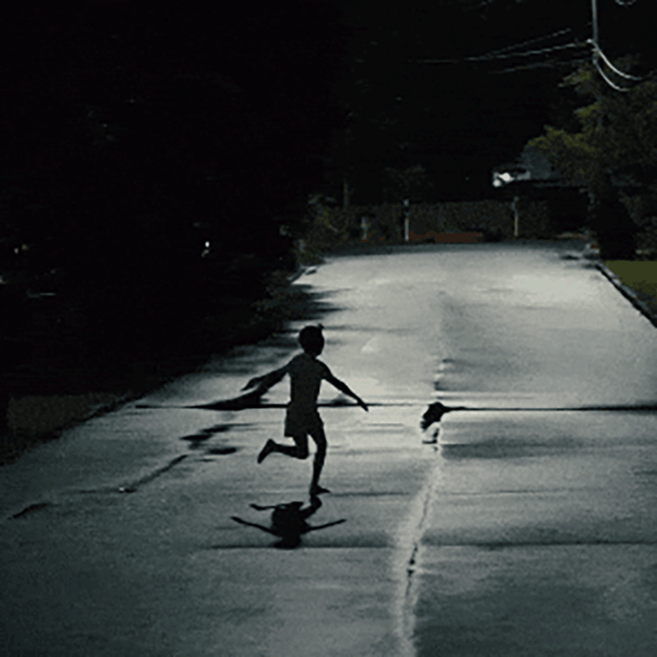 In silhouette against a wet moonlit street a boy runs from left to right, arms held out at his sides in a distinctive pose. Animated gif