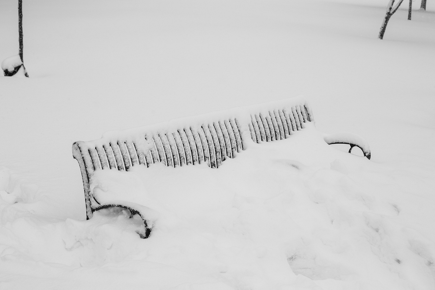 a snow-covered bench in a snowy park