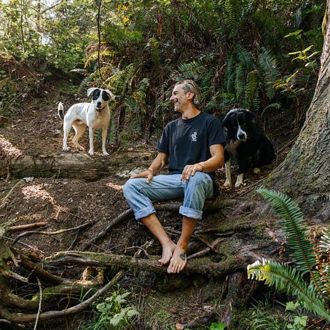 awkward man frolics around stream with dogs wearing very nice merch from be more like your dog