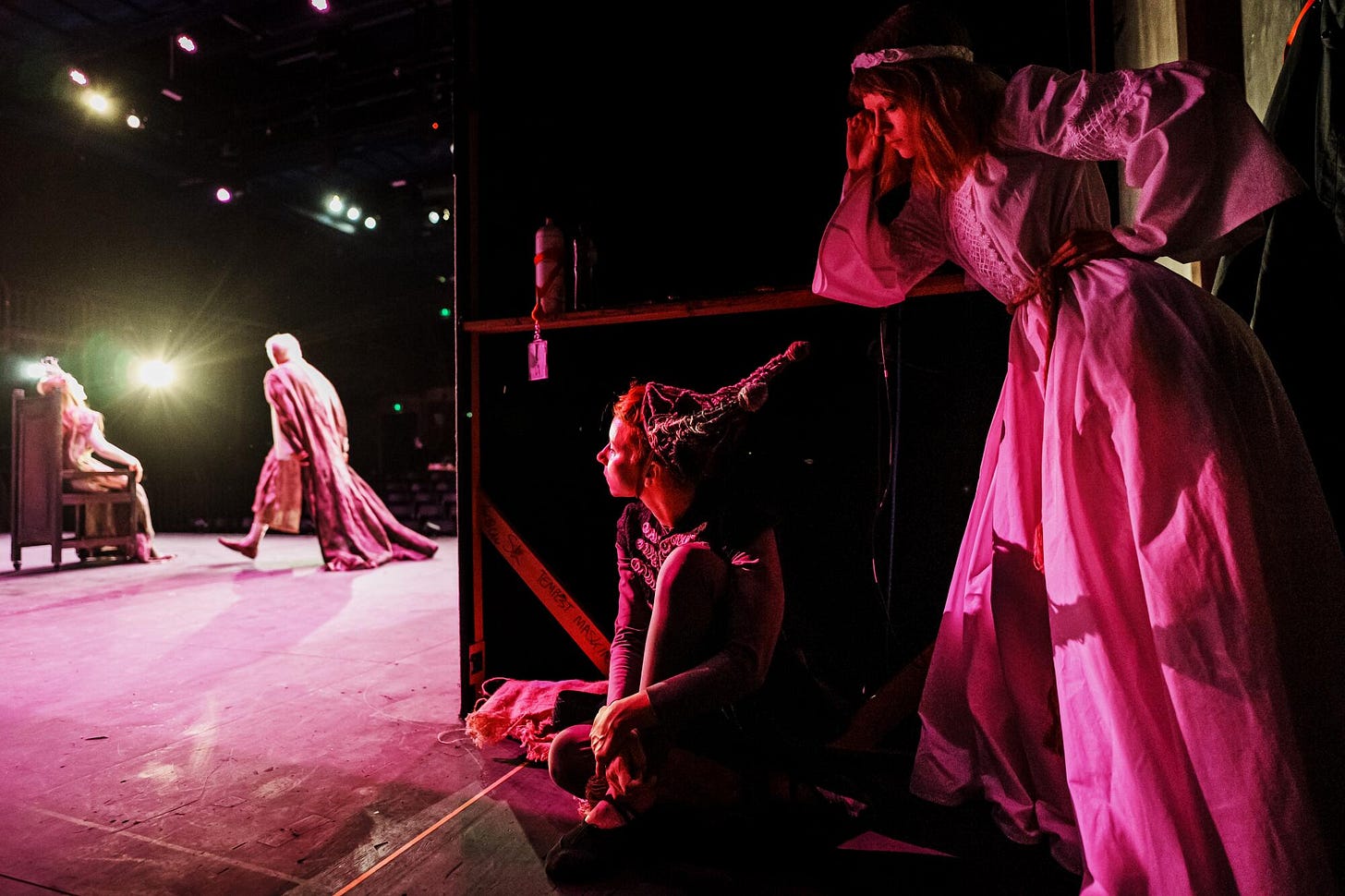 Two people, right, wait backstage during a rehearsal featuring two people onstage.