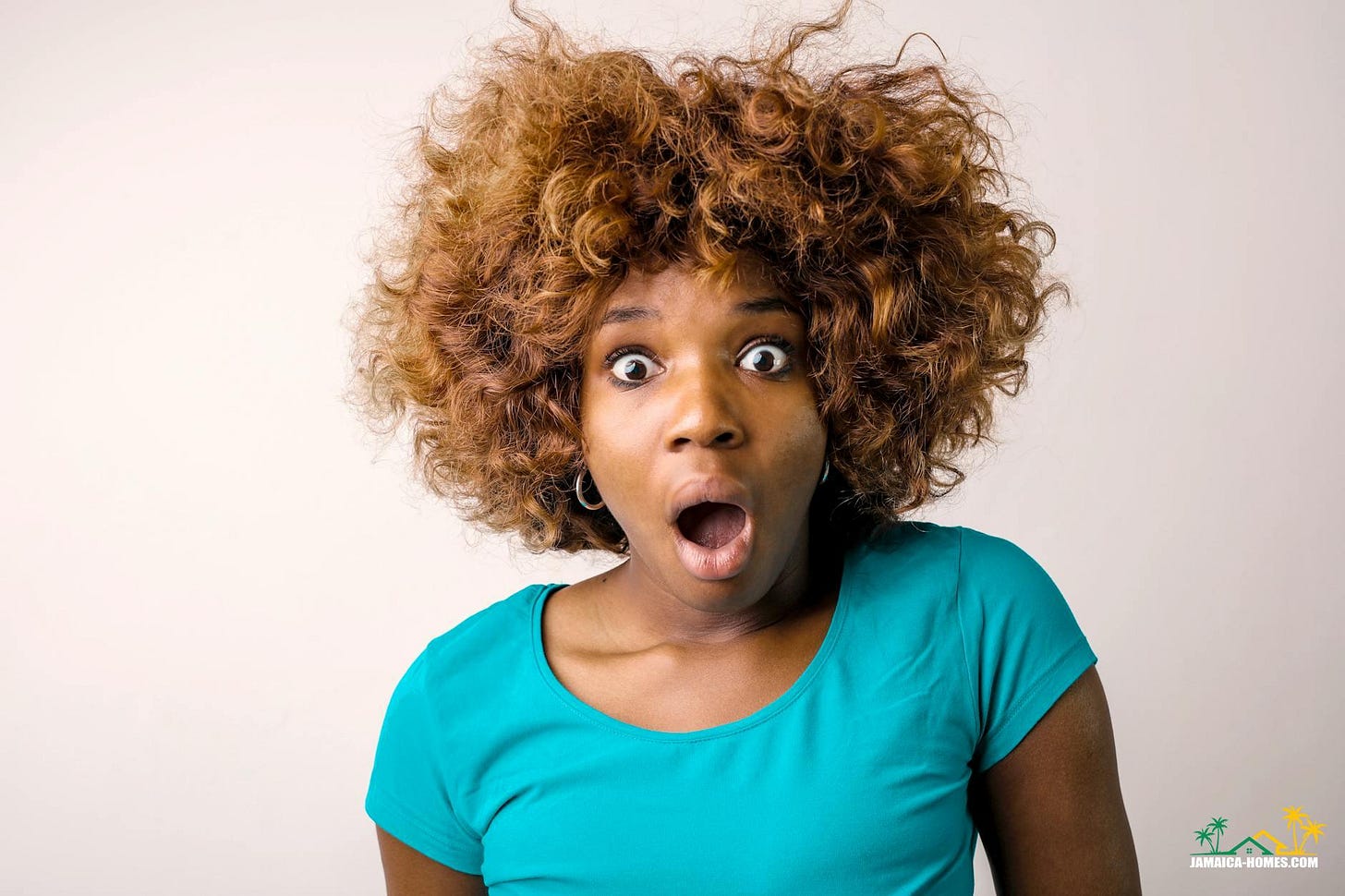 portrait photo of shocked woman in blue t shirt standing in front of white background