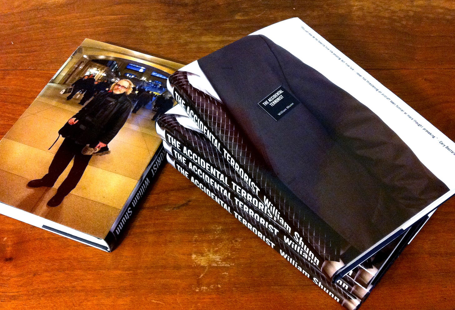 A stack of four copies of an early, privately printed edition of The Accidental Terrorist, next to another copy that is face down exposing the author photo on the back. A stack of four copies of an early, privately printed edition of The Accidental Terrorist, next to another copy that is face down exposing the author photo on the back.