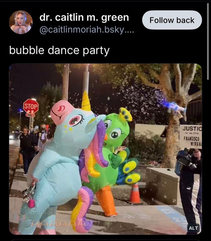 Screenshot of a bunch of folks in front of the Portland ICE building wearing blow up unicorn costumes dancing in bubbles. Text reads: 

dr. caitlin m. green @caitlinmoriah.bsky....
bubble dance party