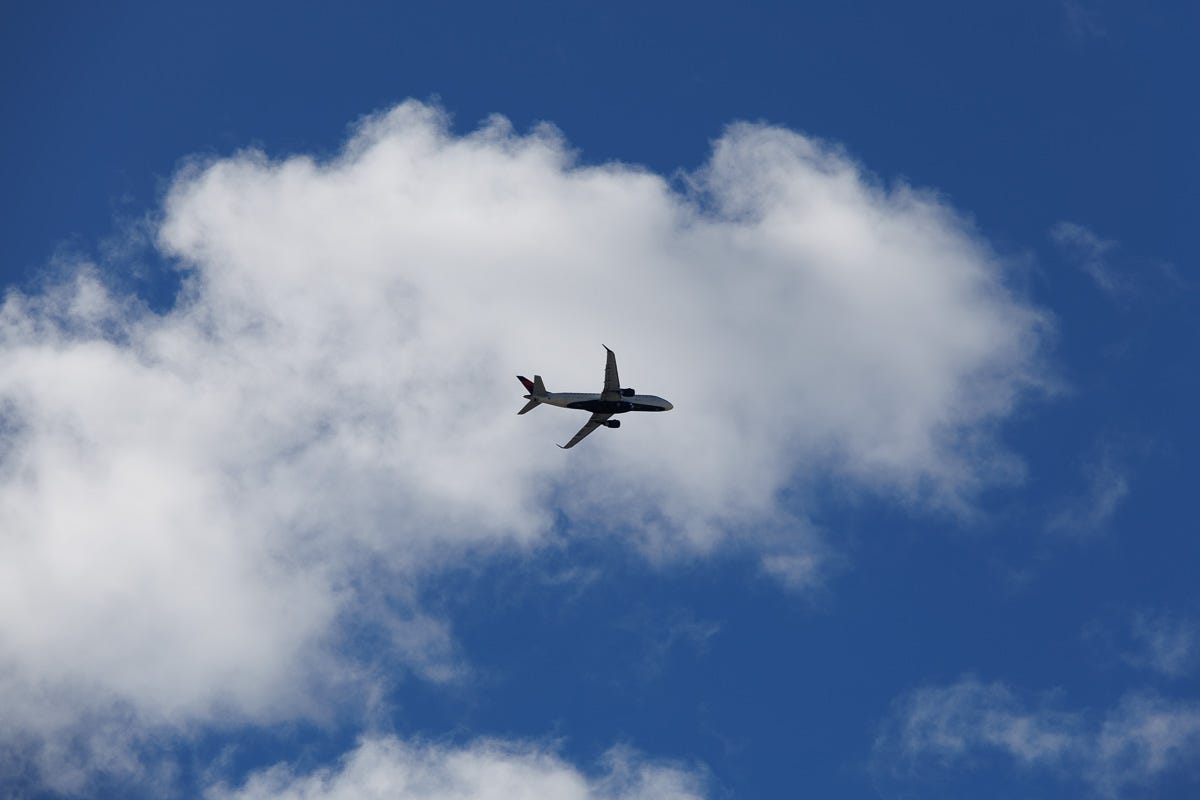 Airplane flying through a soft, textured sky above Boston, centered in cloudscape.