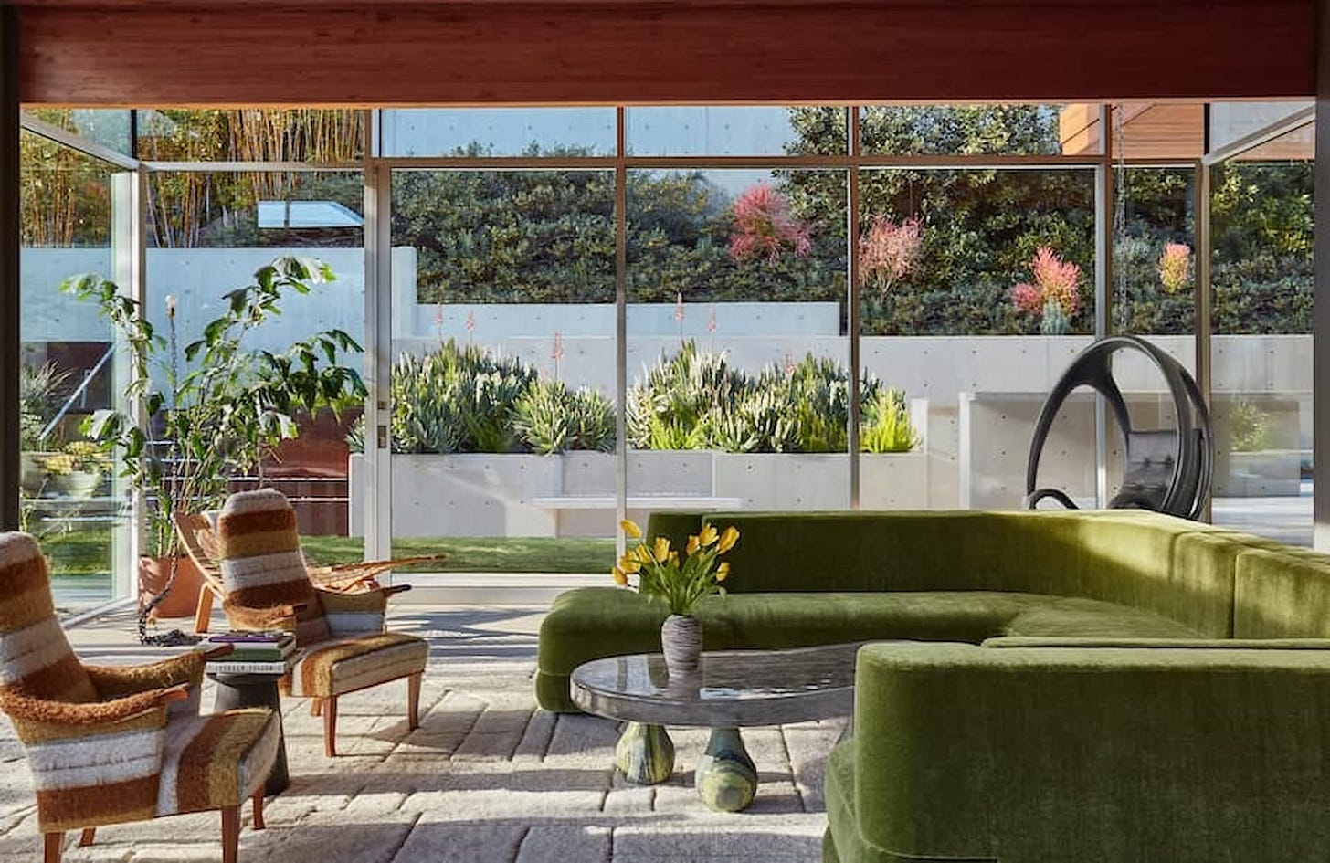glass room with green sofa and brown chairs linking the outside of nature with the inside glass room with green sofa and brown chairs linking the outside of nature with the inside