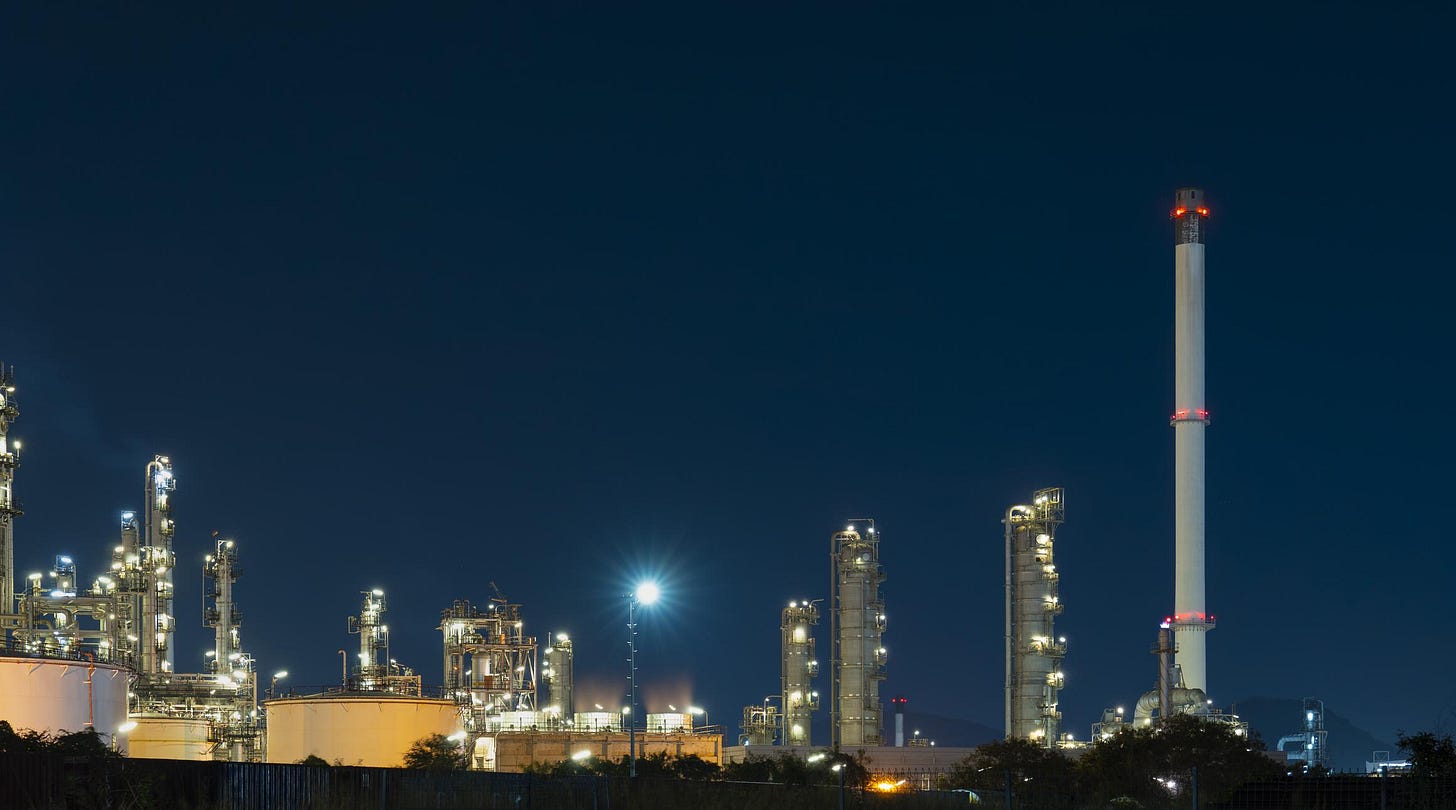 Large industrial Oil refinery plant illuminates the night sky with glowing city lights during oil production.