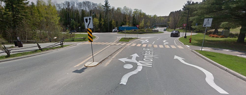 A roundabout with a well marked trail crossing in the foreground.