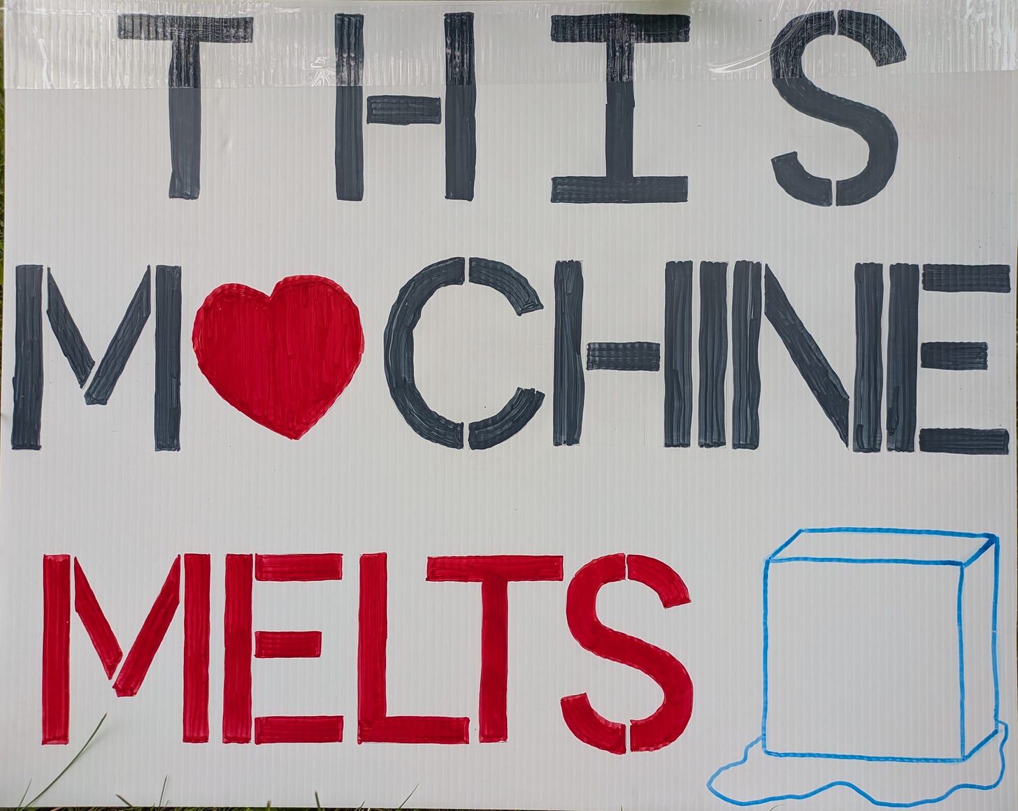 Protest sign that reads THIS MACHINE MELTS ICE (the A is replaced by red heart icon and the word ICE is replaced by an ice-cube). Protest sign that reads THIS MACHINE MELTS ICE (the A is replaced by red heart icon and the word ICE is replaced by an ice-cube).