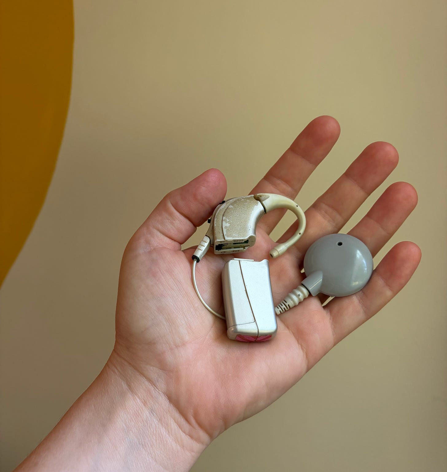 a silver cochlear implant in someone's hand a silver cochlear implant in someone's hand