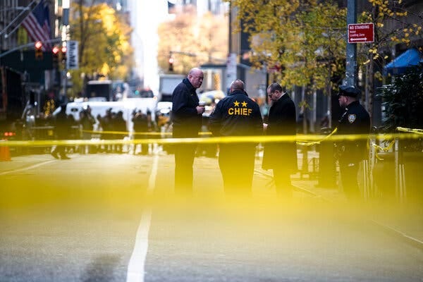 Police officers stand behind yellow tape as members of the public look on. Police officers stand behind yellow tape as members of the public look on.