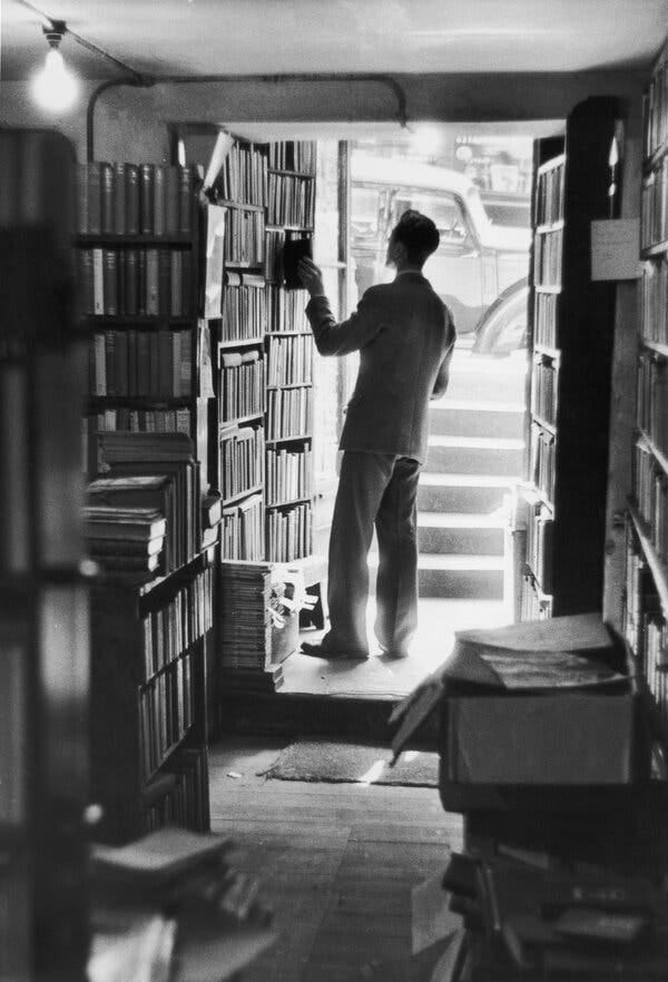 A man browses bookshelves in a photo from the 1950s. A man browses bookshelves in a photo from the 1950s.