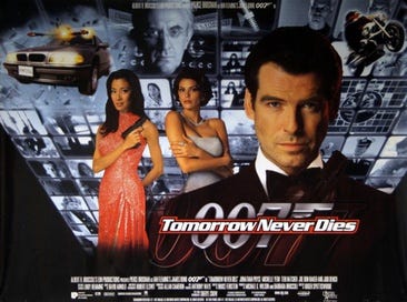 A man wearing an evening dress holds a gun. On his sides are a white woman in a white dress and an Asian woman in a red, sparkling dress holding a gun. On the background are monitors with scenes of the film, with two at the top showing a man wearing glasses holding a baton. On the bottom of the screen are two images of the 007 logo under the title "Tomorrow Never Dies" and the film credits.