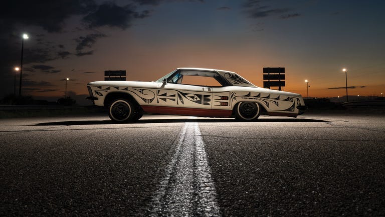rose b. simpson sits on a rolling stool in front of her partially restored 1964 buick riviera in a new mexico auto garage, wearing work pants and kneepads. rose b. simpson sits on a rolling stool in front of her partially restored 1964 buick riviera in a new mexico auto garage, wearing work pants and kneepads.