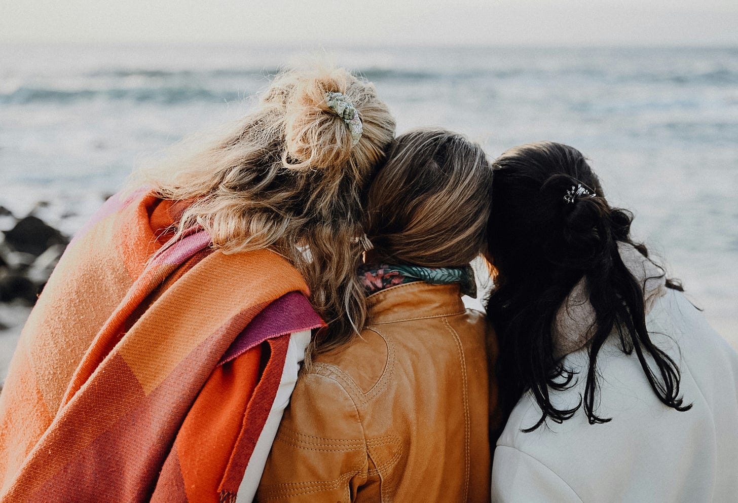 3 women embrace as they look out onto the ocean 3 women embrace as they look out onto the ocean